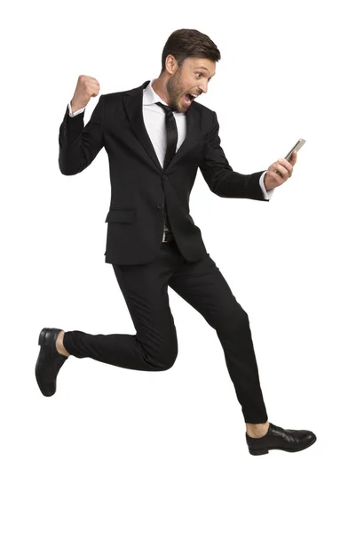 Возбужденный бизнесмен прыгает Холдинг телефон Жест на белом фоне — стоковое фото