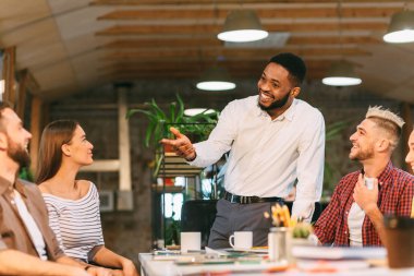 Beyin fırtınası toplantısı. Baş tasarımcı meslektaşlarıyla konuşuyor.