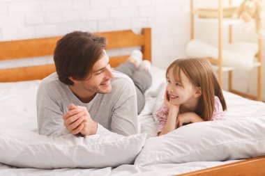 Neşeli baba ve küçük kızı yatakta yatıyor.