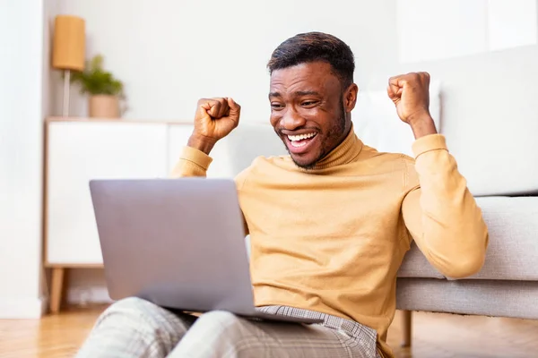 Man Holding Laptop Shaking Fists Sitting On Floor At Home — Stock Photo, Image