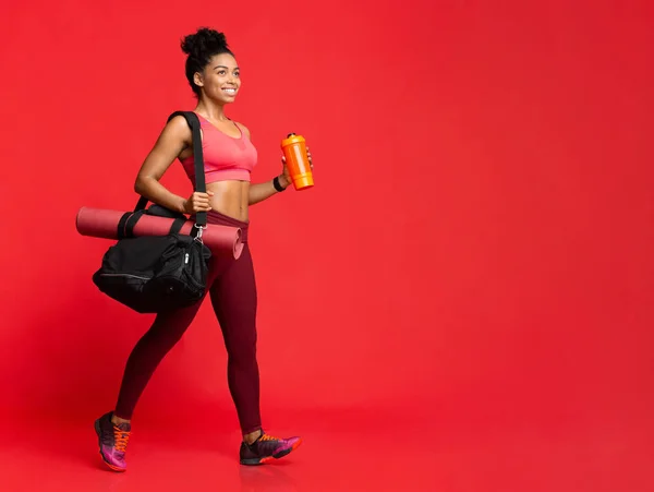 Ragazza che va in palestra con tappetino yoga, borsa e shaker — Foto Stock