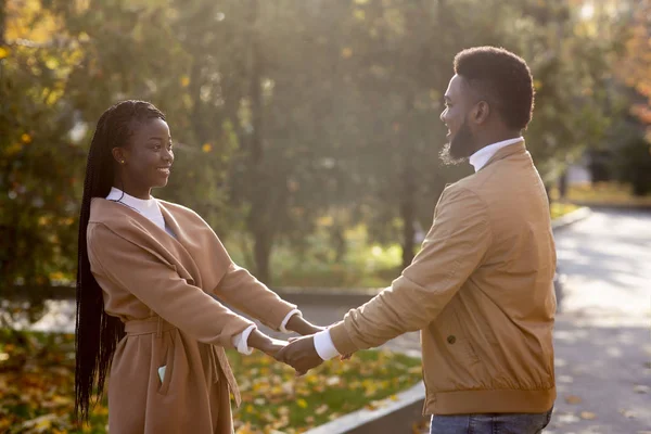 Чёрная романтическая пара, держащаяся за руки во время свидания в осеннем парке — стоковое фото