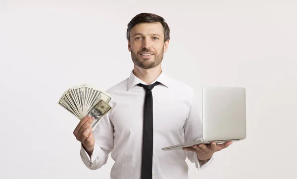 Podnikatel drží peníze a notebook stojí, Studio Shot — Stock fotografie