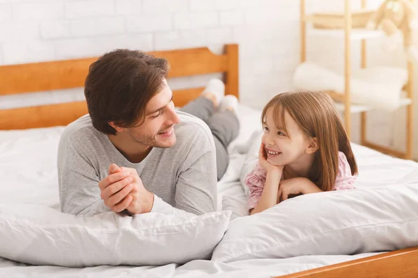 명랑 한 아빠와 침대에 누워 있는 그 의 쓸쓸 한 딸 — 스톡 사진