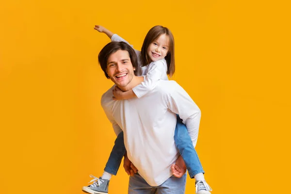 Joyful pai e filha brincando juntos sobre fundo amarelo — Fotografia de Stock