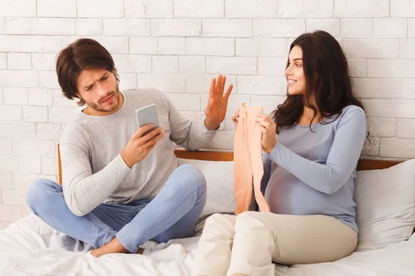 Marido indiferente ignorando sua esposa grávida, usando smartphone no quarto — Fotografia de Stock