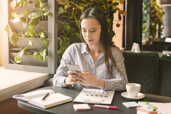 Genç bir kadın cep telefonuyla pazarlama analizi yapıyor. — Stok fotoğraf