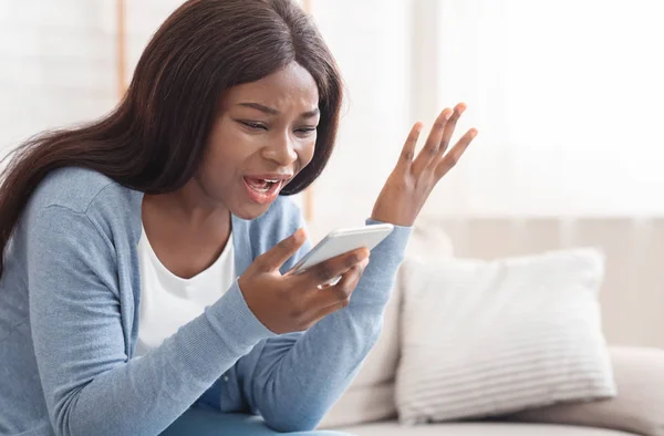Retrato de una joven mujer negra gritando en el teléfono móvil en casa — Foto de Stock