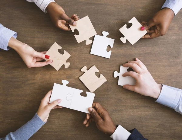 Group of business people assembling jigsaw puzzle together — ストック写真
