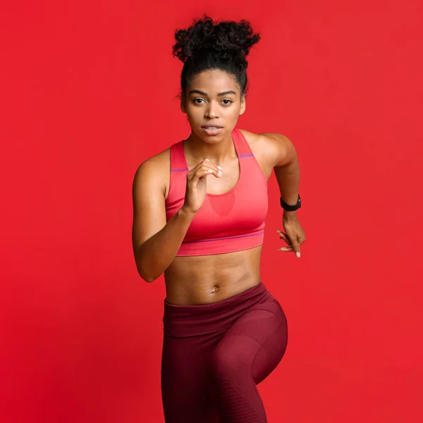 Retrato de correr modelo de fitness africano sobre rojo — Foto de Stock