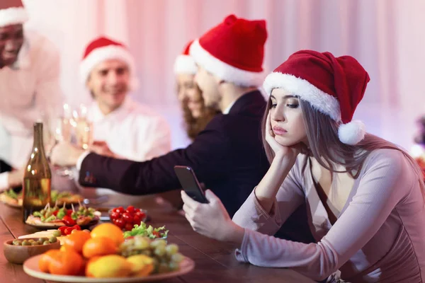 Fille SMS sur le téléphone pendant le dîner du Nouvel An assis à l'intérieur — Photo