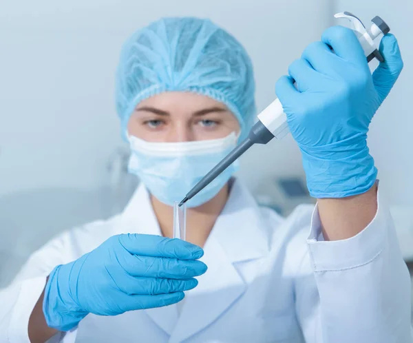 Junge Wissenschaftlerin wirft Proben aus Pipe in Reagenzgläser — Stockfoto