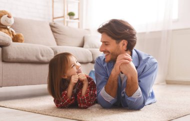 Neşeli baba ve liitle kızı yerde yatıyor