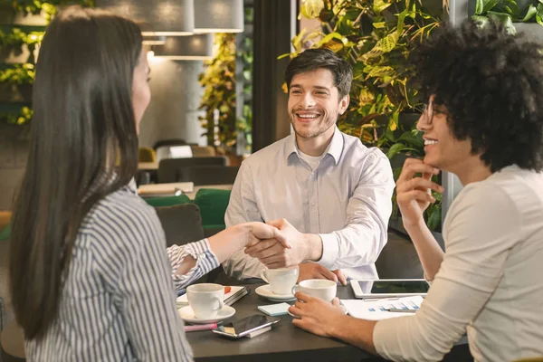 Millennial persone strette di mano dopo aver raggiunto un accordo in caffè — Foto Stock