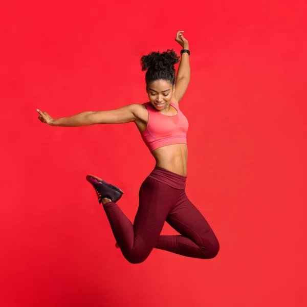 Счастливая атлетичная девушка в спортивной форме прыгает вверх — стоковое фото