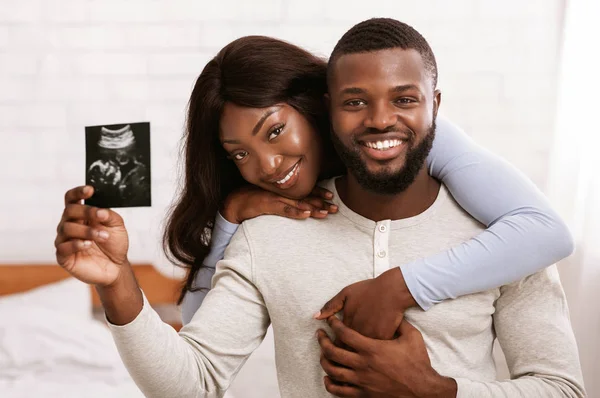 Wesoła para małżeńska trzymająca ultradźwiękowy obraz swojego dziecka — Zdjęcie stockowe