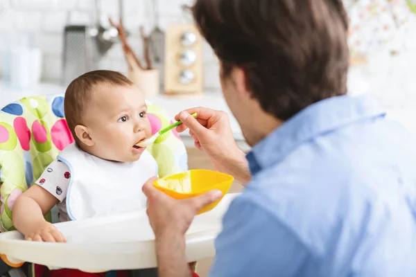 Отец кормит своего любопытного маленького сына на кухне — стоковое фото
