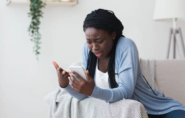 Mujer negra frustrada que tiene problemas con el teléfono inteligente en casa — Foto de Stock