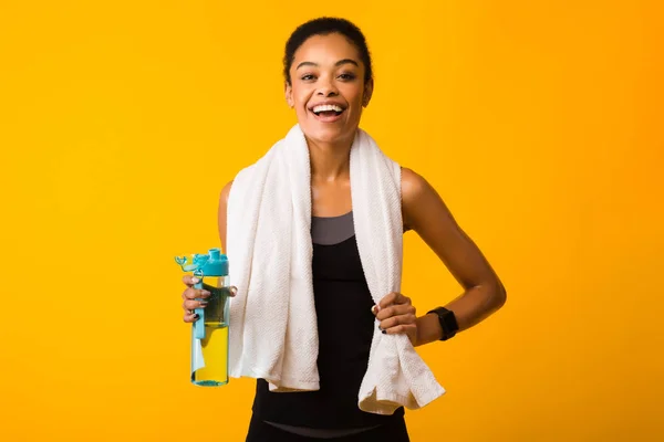 Allegro donna tenendo bottiglia di acqua sorridente in piedi in studio — Foto Stock