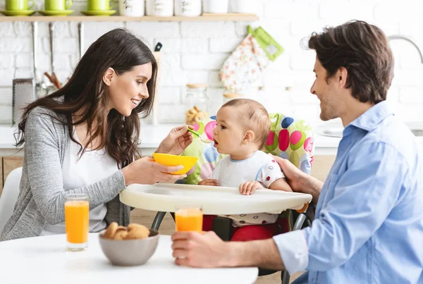 Glückliche Eltern füttern kleinen Jungen in der Küche — Stockfoto