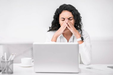 Yorgun bir yönetici kadın, burun ve göz masajı yapıyor.