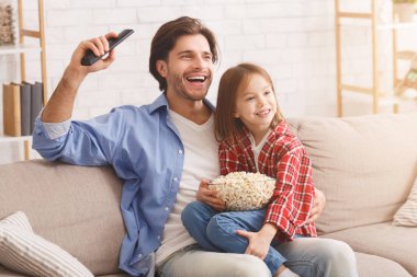 Baba ve kızı televizyonda futbol maçı izliyorlar.