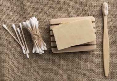 Bamboo toothbrush, cotton buds and cocoa soap on eco canvas clipart