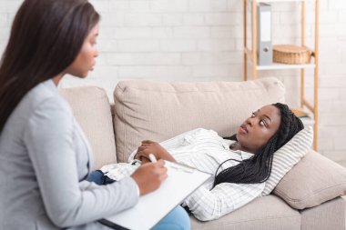 Depresyondaki afro kadın kişisel danışmanlıkta psikoterapistle sorunlarını tartışıyor.