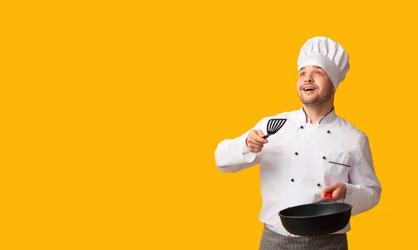 Szef kuchni Guy Holding Pan rzucanie niewidzialne jedzenie na stojąco, Studio Shot — Zdjęcie stockowe