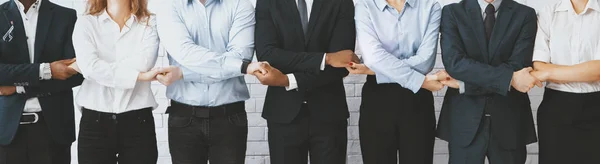 Business team holding hands, standing in row