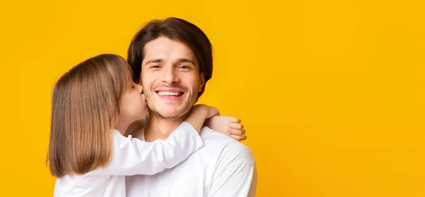 Маленькая девочка целует своего счастливого отца на жёлтом фоне — стоковое фото