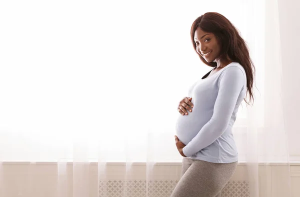 Feliz mulher grávida tocando sua barriga em casa — Fotografia de Stock