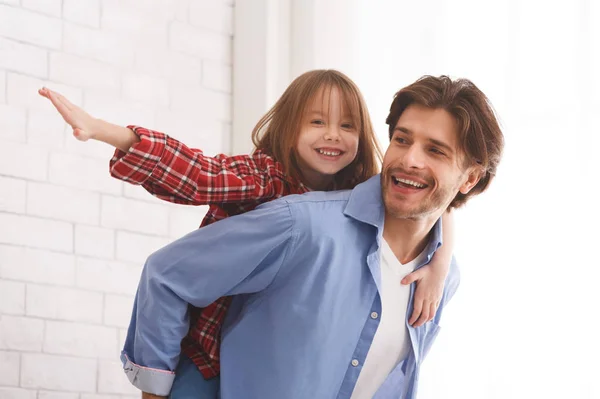 Happy young dad holding his daughter on his back — Stock Photo, Image