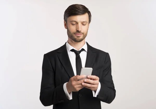 Homem de terno usando mensagens de telefone com colegas, fundo branco — Fotografia de Stock