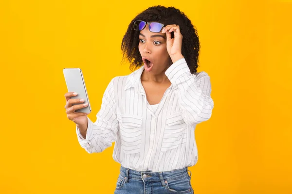 Close-up portret van verrast Afrikaans meisje op zoek naar telefoon — Stockfoto