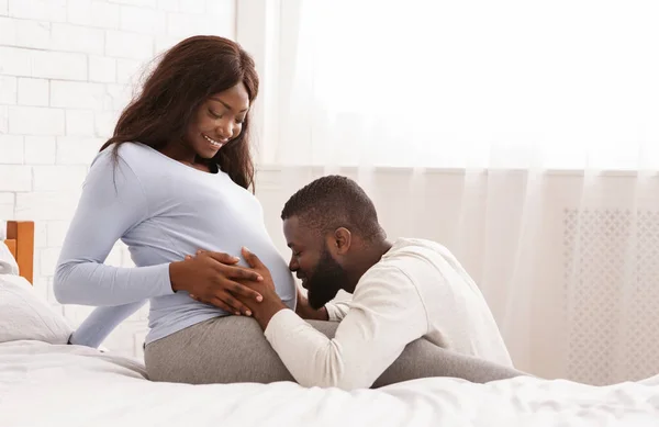 Блаженний чоловік цілує свою щасливу вагітну дружину живіт — стокове фото