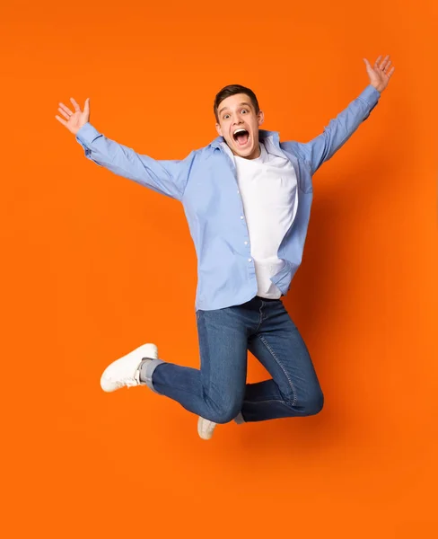 Zabawny portret nastolatka facet skacze na pomarańczowym tle — Zdjęcie stockowe