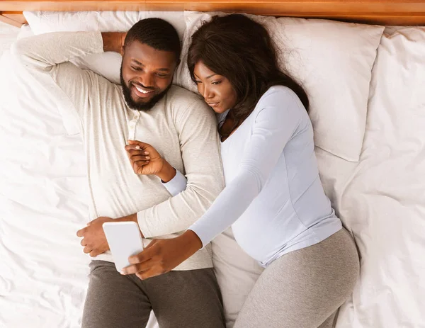 Getrouwd zwanger paar nemen selfie terwijl rusten op bed — Stockfoto