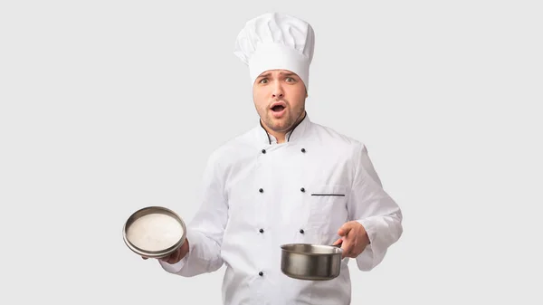 Intrigado Cook Man abrindo panela de pé no fundo do estúdio branco — Fotografia de Stock