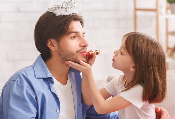 Primer plano de niña pequeña poniendo lápiz labial en los labios de papá —  Fotos de Stock