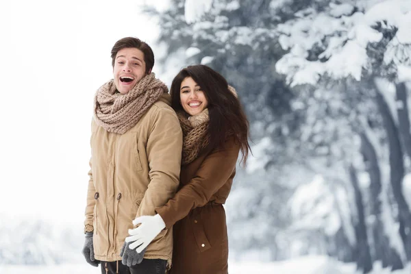 Mann und Frau lächeln in die Kamera und posieren im verschneiten Wald — Stockfoto
