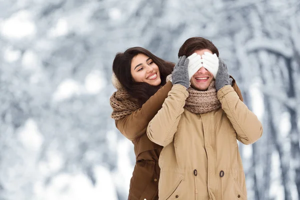 Flicka som sluter sina pojkvänner ögon gå tillsammans i vinterskogen — Stockfoto
