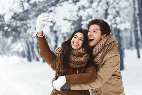 Amorosos cónyuges tomando selfie tener al aire libre fecha en el parque cubierto de nieve —  Fotos de Stock