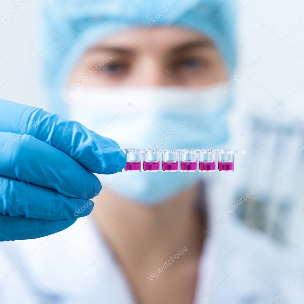 lurred Woman in mask and latex gloves preparing pink samples for machine testing