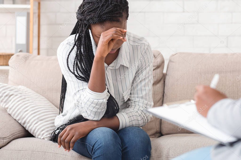 Desperate black woman sitting on personal consultation at psychologists office