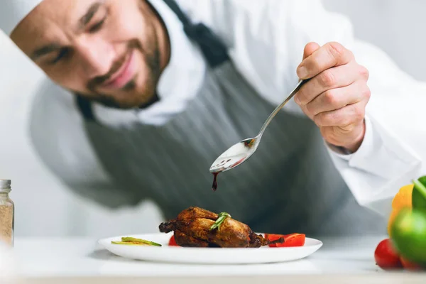 Chef koken voedsel gieten saus op kip schotel in de keuken — Stockfoto