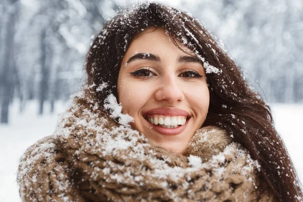 Jovencita alegre con nieve en el pelo sonriendo de pie en el bosque —  Fotos de Stock
