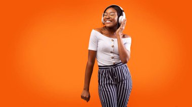 Joyful Afro Lady In Headphones Listening To Music, Studio, Panorama clipart