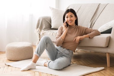 Hoş bir karar. Evde cep telefonuyla konuşan Asyalı bir kız.