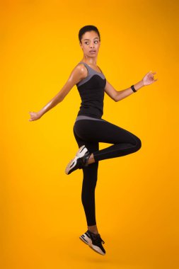 Siyah Kadın Atlama Egzersizi Stüdyoda Sarı Arkaplan Üzerinde